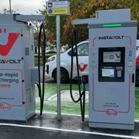 A pair of InstaVolt ultra-rapid EV chargers located in a car park, featuring clear signage and branding, with an InstaVolt service van parked behind.