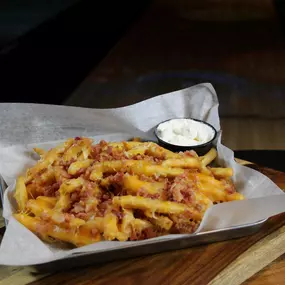 A generous portion of french fries topped with melted jack, cheddar cheese, and bacon