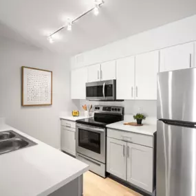 Spacious kitchen with stainless steel appliances, white cabinets, and white quartz countertops.