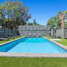 Outdoor swimming pool surrounded by turf and lounge chairs.