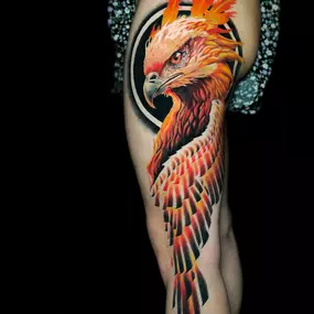 ein großer Phoenix, mit Kopf und teilweise Flügeln. Starkes rot und orange. Hinter dem Kopf ein dunkler Kreis, geht bis leicht unters knie. seitlich am Oberschenkel angebracht.