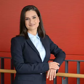 Businessportrait einer Kundin im Gebäude-Atrium: rote Strukturwand als klarer Hintergrund, Geländer als Leading Line, weiches Tageslicht. Professioneller Look für LinkedIn, Website und Bewerbung – fotografiert von ‚ANNETTE STIER – Fotografie‘ in Bensheim.