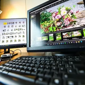 Innenraum: Bildbearbeitungsplatz mit zwei Monitoren, Tastatur und RAW-Fotos auf dem Screen – professionelle Postproduktion.