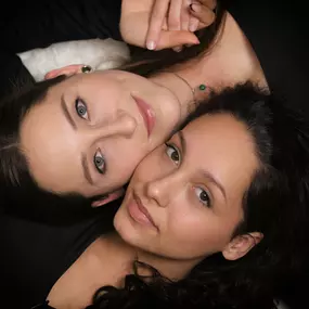 Zwei Frauen liegen Kopf an Kopf, von oben fotografiert, schauen in die Kamera; Close-up mit weichem Beauty-Licht.