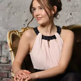 Portrait einer Kundin im Studio: sitzend auf Vintage-Sessel vor texturierter Wand, weiches, formgebendes Licht und klare Bildführung. Professioneller Look für Portrait, Sedcard oder Personal Branding – fotografiert von ‚ANNETTE STIER – Fotografie‘.