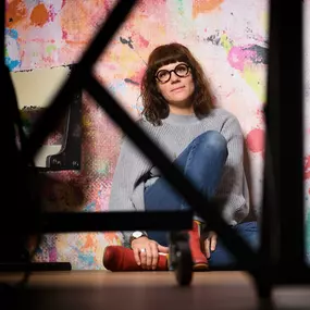 Selbstportrait der Fotografin/Inhaberin Annette Stier im Studio Bensheim; sitzend vor Farbwand, Stativ vorn, Fernauslöser.