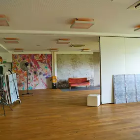 Großer Studio-Raum in Bensheim mit Holzfußboden, Set-Wänden, farbigem und Beton-Hintergrund, Blitzstativen, Equipmentwagen und Vintage-Sofa.