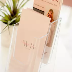Westhafen Beauty Ein transparenter Flyerhalter präsentiert ästhetisch gestaltete Informationsbroschüren zu professionellen Hautpflegeleistungen.