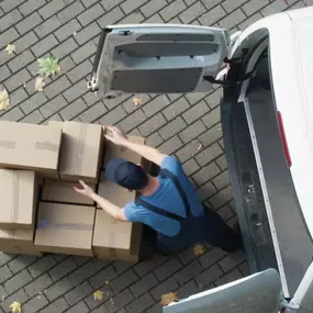 Person lädt Umzugskartons in einen Transporter, Ansicht von oben