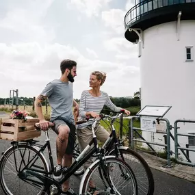 Couple standing with their bicycles in front of the ‘Dicke Berta’ lighthouse