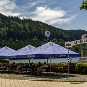 Der Biergarten des Maritim Hotels Titisee lädt mit gemütlichen Sitzplätzen im Freien und rustikalem Charme zum Entspannen ein. Gäste genießen erfrischende Getränke und Snacks in einer angenehmen Umgebung.