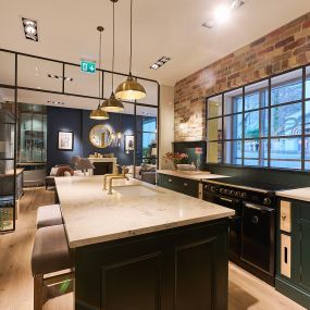 Die Küche von Thomas Homes verfügt über ein modernes Farbschema und ein edles Design, das ein luxuriöses Gefühl vermittelt.