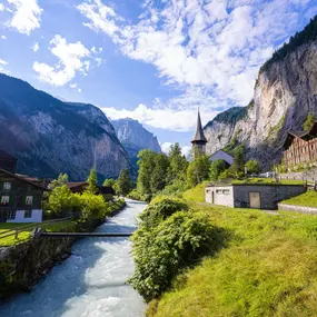 Die Lütschine fliesst durch das Dorf Lauterbrunnen. Die Kirche steht neben dem Fluss und zwischen steilen Felsen des Lauterbrunnentals.