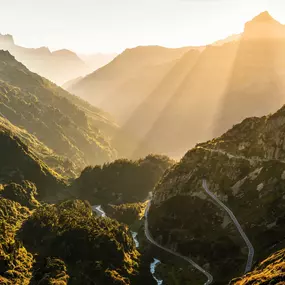 Die Passstrasse am Sustenpass verzweigt sich dur die mit Büschen überwachsene Felsenwelt. Die Sonneneinstralung am Abend verleiht der Landschaft eine romantische Stimmung.