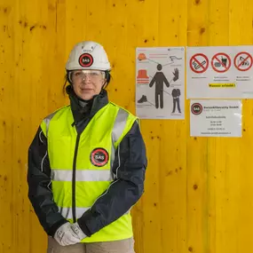 Ein Swiss All Security Mitarbeiter kontrolliert den Zutritt zu einer Baustelle, indem er Ausweise überprüft und Sicherheitsprotokolle einhält, um Unbefugte abzuwehren.