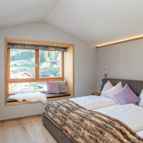Schlafzimmer mit Doppelbett und Sitzfenster - Alpegg Chalets in Waidring, Tirol.