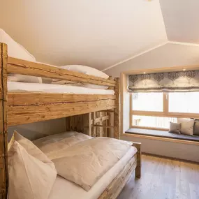 Kuscheliges Ambiente mit Holzbett und Window Seat in den Chalets von Alpegg in Waidring, Tirol.