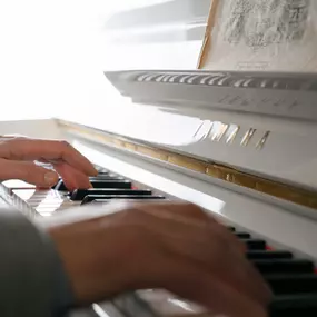 Hände spielen auf einem weißen Yamaha-Klavier