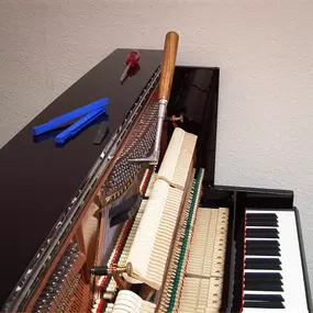 Klavier in geöffnetem Zustand mit Stimmhammer und Werkzeug. Darstellung des Prozesses der Klavierstimmung für einen reinen und harmonischen Klang.