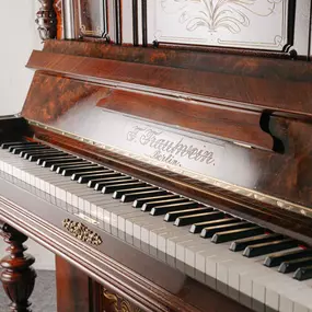 Ein antikes Klavier von F. Trautwein aus Berlin mit edler Holzverarbeitung und kunstvollem Design. Ein Beispiel traditioneller Klavierbaukunst aus Deutschland.