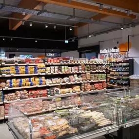 Innenansicht des tegut... Supermarktes mit verschiedenen Brotsorten im Vordergrund und Feinkost-Bedientheken im Hintergrund.