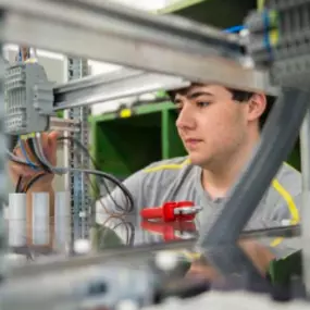 Elektriker Lehrling bei der Arbeit an einem Schaltkasten.