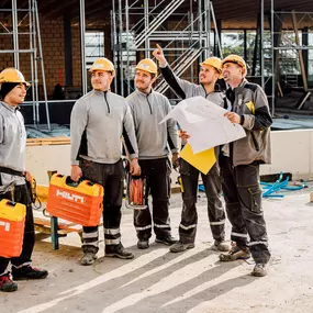 Drei unserer Servicetechniker Lehrlinge die mit ihrem Vorgesetzten zusammen den Elektroplan auf der Baustelle des Kongresshauses studieren.