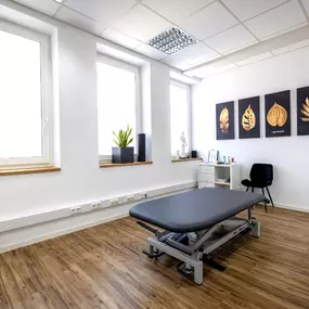 Das Bild zeigt einen Behandlungsraum mit einer Liege und einem Skelettmodell – zur Veranschaulichung anatomischer Strukturen während der Therapie.