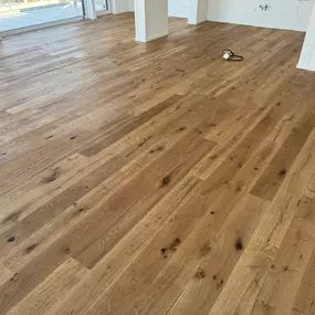 Das Bild zeigt einen edlen Parkettboden aus Eiche-Landhausdielen in einem lichtdurchfluteten Penthouse. Die Dielen wurden präzise verlegt und unterstreichen den hochwertigen Charakter des Raums.