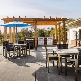 Outdoor grilling area with cabana seating and tables.