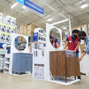 Lowe's team member assisting customer shopping in the Fashion Bath aisle.