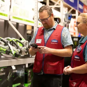 Two Lowe's Home Improvement employees assisting in power tools aisle.