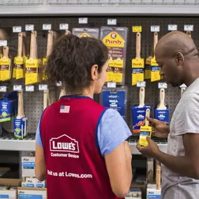 Lowe's team member helping a man select paint brushes.