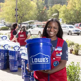 Lowe's team member holding iconic blue Lowe's bucket.