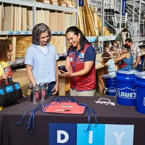 Lowe's team member helping a mother and daughter at a DIY kid's workshop.