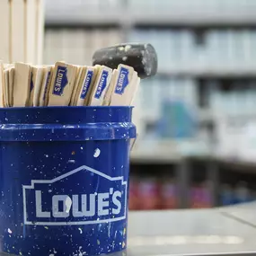 Close up of Lowe's blue bucket with paint sticks.