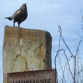 Basaltzuil met bronzen vogel