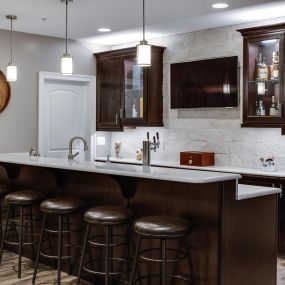 A wet bar design in a dark espresso cabinet finish features nicely in a finished game room or basement area.  The more seats the merrier!