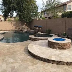 New construction freeform pool with spa spillover, firepit, and pavers