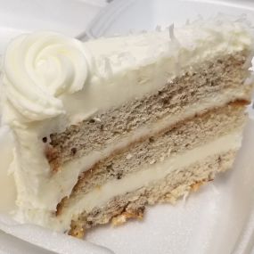 Smooth and delicious Italian Cream Cake. Vanilla buttercream cake with shaved coconut sprinkled on top with thick layers of buttercream icing inbetween and coated on top.