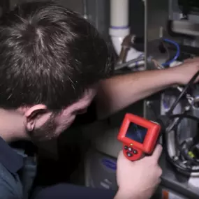 King Heating technician inspecting a furnace with a camera.