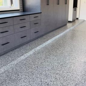 Premier garage can update your garage to look like this! These are our Windswept Pewter cabinets with matte black handles, ebony star countertop, gray slat wall, and storm color epoxy flooring.