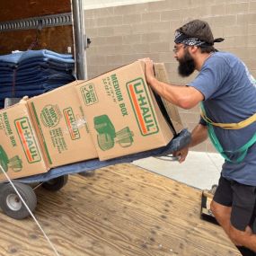 Aaron Movers employees moving boxes on a dolly.