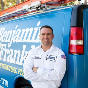 Plumber outside leaning on a Benjamin Franklin Plumbing van in the Myrtle Beach & Conway area.