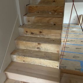 Installing new Red Oak treads and risers on a builder plywood stairs after the old carpet was removed.