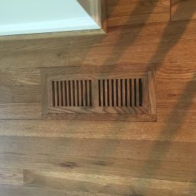 We install oak vents that are flush with the floor.  They are stained and finished to match the floors. They also have a damper for air flow control.