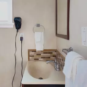 A hair dryer, towels, a sink, and a mirror