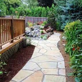 A Greenhaven Landscapes design customer's Vancouver WA back yard with stone walkway, and beautiful greenery lining the path