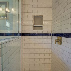 A decorative tile stripe dresses up a white subway tile shower.