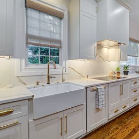 Quartz backsplash with gold vein alongside gold hardware throughout white kitchen